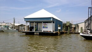 A floating structure with a white roof and blue walls, featuring a sign with a logo and contact number. - HONEYHOLE 3BR.  Beautiful, spacious, and best of all...NO BUNK BEDS! (Venice)