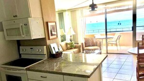 Una cocina con microondas, estufa y comedor con vista al océano.