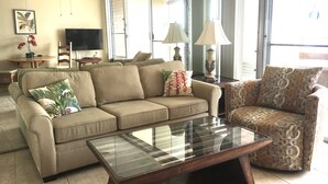 Una sala de estar con sofá, sillón y una mesa de centro de vidrio.