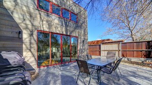 Een modern huis met terras, voorzien van een glazen deur, een eettafel en tuinmeubilair.