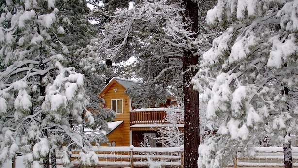 A wooden cabin surrounded by snow-covered trees.