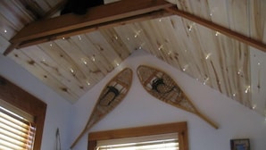 A room with a sloped ceiling, wooden beams, and two woven baskets hanging on the wall.