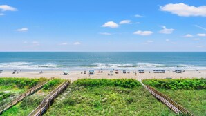 A beach with a wooden boardwalk leading to the shore, sandy beach, and the ocean.