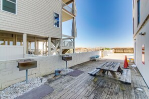 Eine Holzterrasse mit Picknicktisch, Grill und einem kleinen Poolbereich.