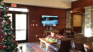 A lobby with a Christmas tree, a television mounted on the wall, a fireplace, and leather seating. - Rimfire Lodge 307 - Deluxe Full Studio with Full Kitchen, Sleeps 4 (Snowshoe)