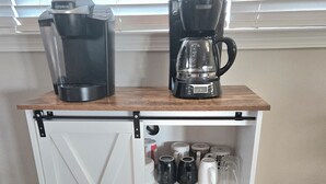 A kitchenette with a coffee maker, a blender, a crockpot, and various mugs.