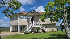 A two-story house with a front porch, a staircase, and a flag.