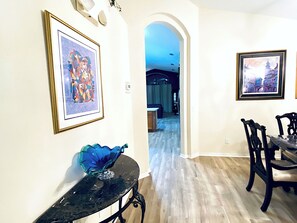 A dining area with a table and chairs, a framed picture on the wall, and a hallway leading to another room. - Water Front Villa in Emerald Island, 3 Mi to Disney, 4BdRm/3Ba,Theme Rm,Pool (Kissimmee)