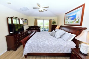 A bedroom with a large bed, wooden dresser, and a ceiling fan. - Water Front Villa in Emerald Island, 3 Mi to Disney, 4BdRm/3Ba,Theme Rm,Pool (Kissimmee)
