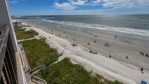 A beach with a clear sky, a sandy shore, and a building in the foreground. - 10% off  3-7 nights thru Oct. Cherry Grove. 3BR 3BA OF condo. Sleeps 8. (North Myrtle Beach)