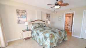 A bedroom with a bed, two bedside tables, a ceiling fan, and a door leading to another room. - 10% off  3-7 nights thru Oct. Cherry Grove. 3BR 3BA OF condo. Sleeps 8. (North Myrtle Beach)