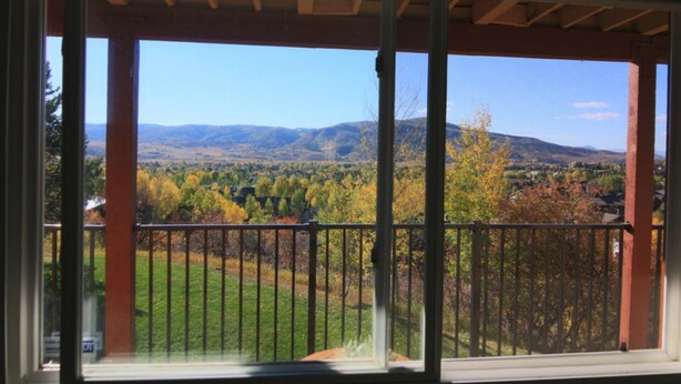 A balcony with a view of a mountainous landscape and autumn foliage.