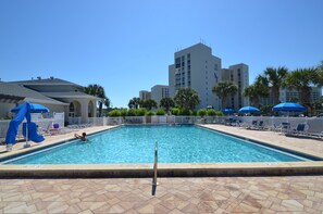 A swimming pool with a lifeguard stand, lounge chairs, and umbrellas.