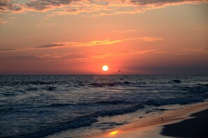 Ein Sonnenuntergang über dem Meer, die Wellen nähern sich dem Ufer.