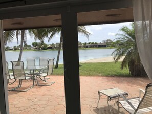 A patio with chairs and a table overlooking a lake, surrounded by palm trees and houses. - Lakeside Miami, Designed for Superior Comfort, close to everything Kendall (Miami)