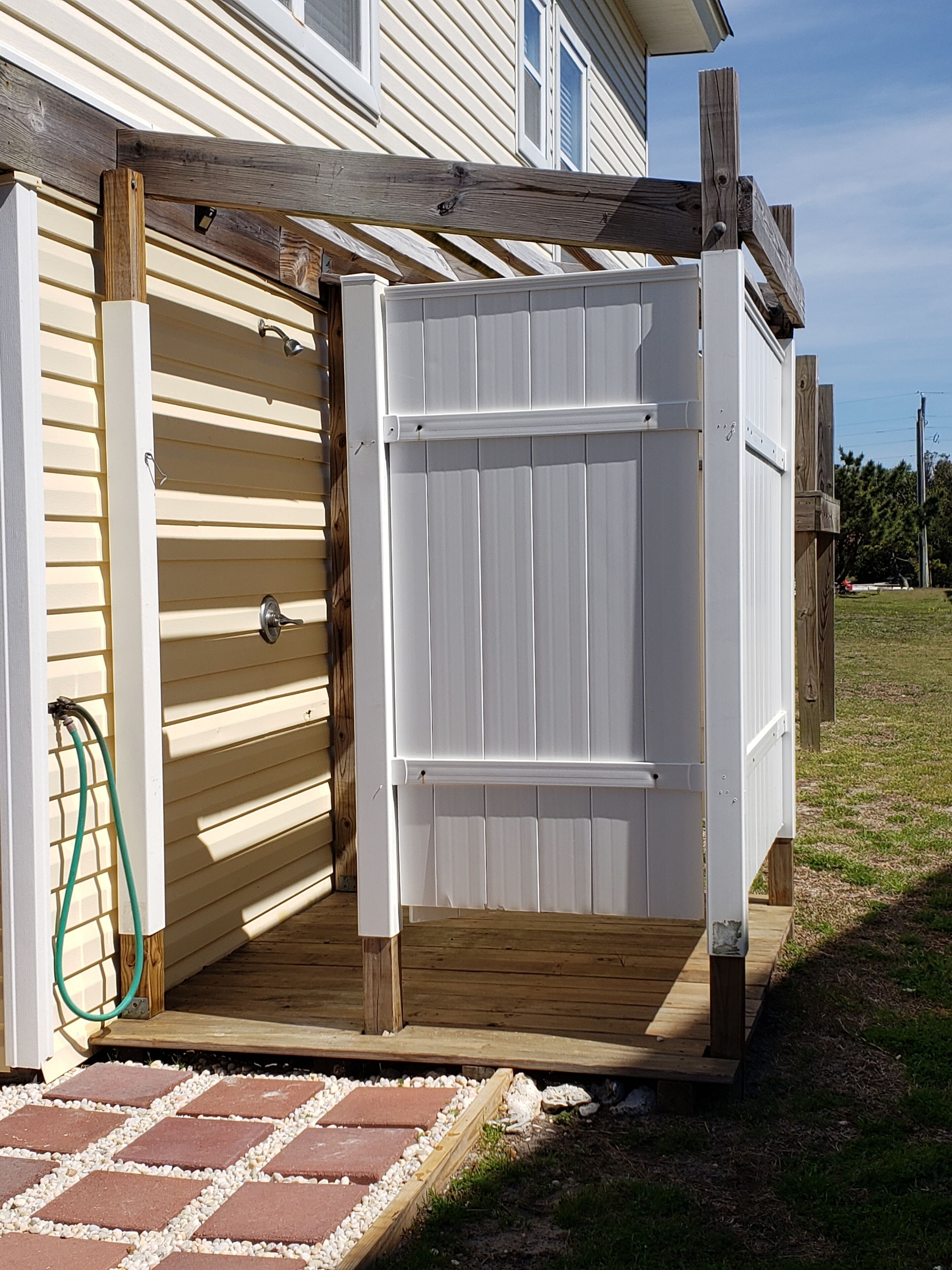 A wooden deck with a white gate leading to a covered outdoor area.