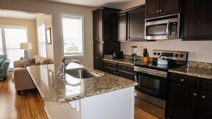 Una cocina moderna con armarios de madera oscura, electrodomésticos de acero inoxidable y encimera de granito.