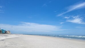 Una playa con cielo despejado, orilla de arena y edificios a lo largo de la costa.