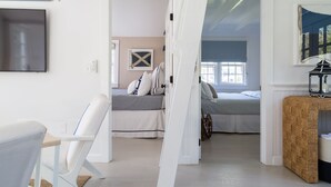 A modern bedroom with a bed, a chair, and a television. - New In Town Time & Tide Cottage (Nantucket)
