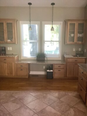 Una cocina con armarios de madera, una ventana con persianas y una planta en el alféizar.