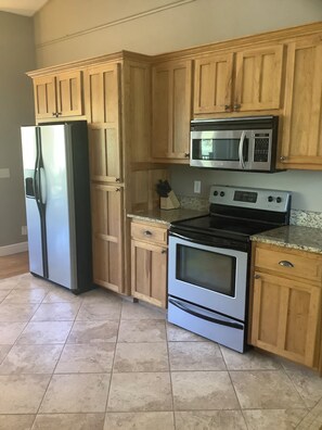 Una cocina con armarios de madera, un refrigerador de acero inoxidable, un microondas y un horno.