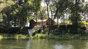 Una cabaña junto al lago con una terraza de madera y una escalera que lleva a un porche.