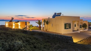 A coastal building with a stone facade, a balcony, and a view of the sea at sunset. - Seafront Junior Villa with private heated Jacuzzi (Chania)