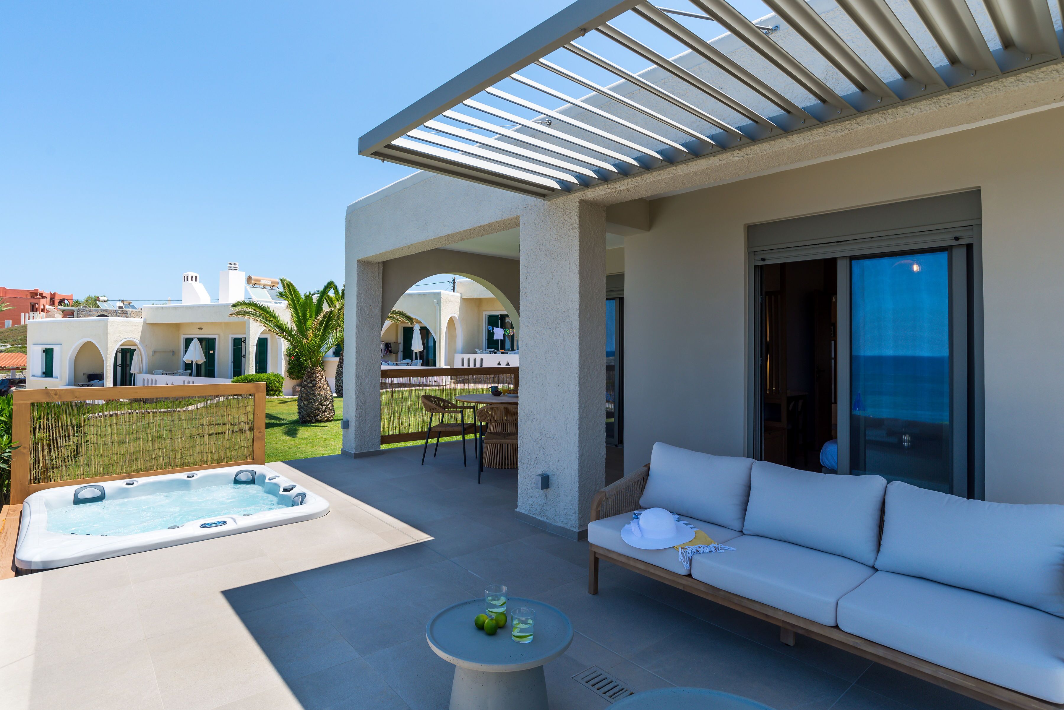 Un patio exterior moderno con un jacuzzi, un sofá y una mesa con bebidas.