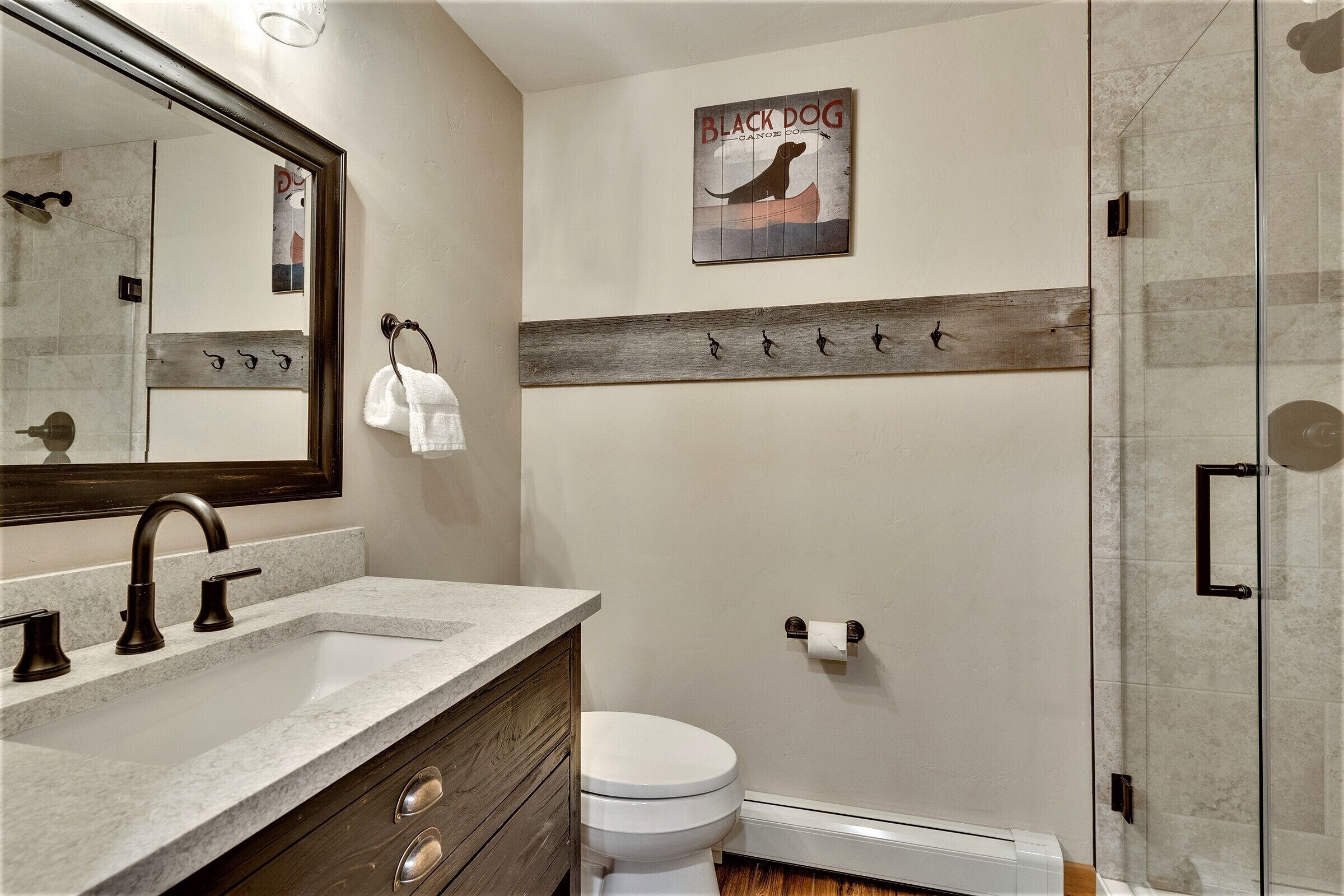 A bathroom with a shower, a toilet, a sink with a mirror, and a towel rack.