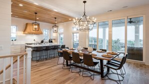 A spacious kitchen with a central island, large windows, and a dining area with a view. - Coastal Manor~ 6 bdrm, across from ocean,  Ocean Views!, Private Pool and Hot Tub, Elevator! (Isle Of Palms)