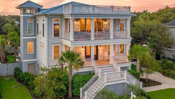 A large, two-story house with a balcony on the second floor, surrounded by lush greenery. - Coastal Manor~ 6 bdrm, across from ocean,  Ocean Views!, Private Pool and Hot Tub, Elevator! (Isle Of Palms)