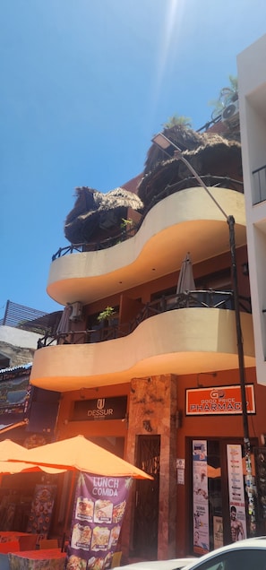 A multi-story building with a restaurant on the ground floor, a pharmacy on the second floor, and a balcony with a thatched roof. - Beach Break Suites, 1 BR Suites Just Steps from Sayulita's Action (Sayulita)