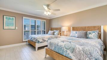 A bedroom with two beds, a ceiling fan, a window with blinds, and a framed picture on the wall.