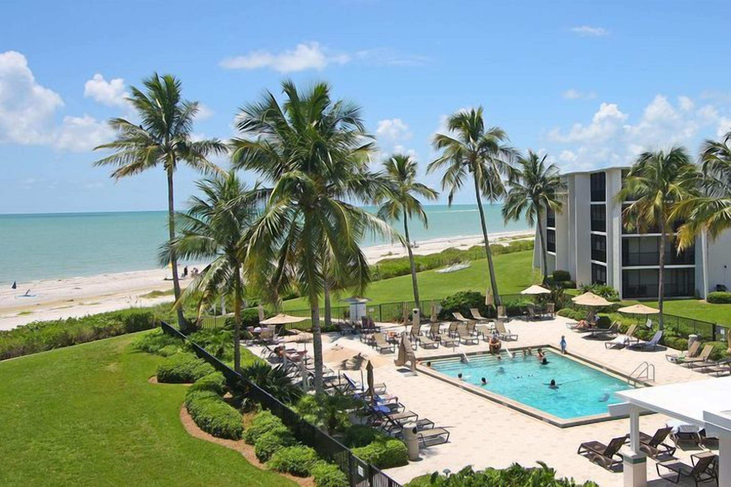 A resort with a swimming pool, palm trees, and a beach view.