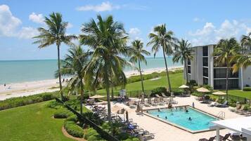 A resort with a swimming pool, palm trees, and a beach view.