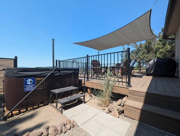 Una terraza con mobiliario exterior, bañera de hidromasaje y una zona con sombra.