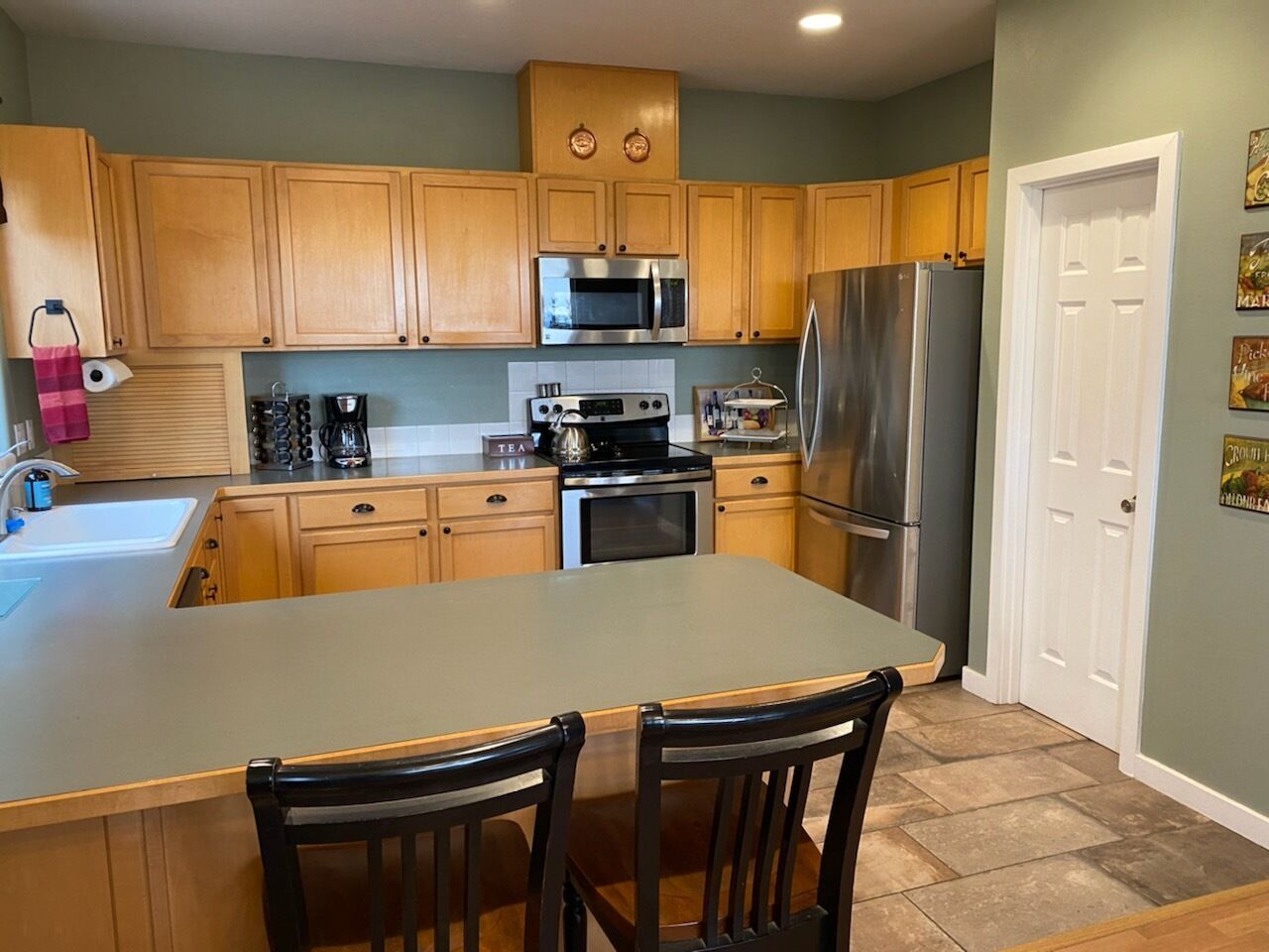 A kitchen with wooden cabinets, a stainless steel refrigerator, a microwave, and a coffee maker.