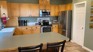 A kitchen with wooden cabinets, a stainless steel refrigerator, a microwave, and a coffee maker.