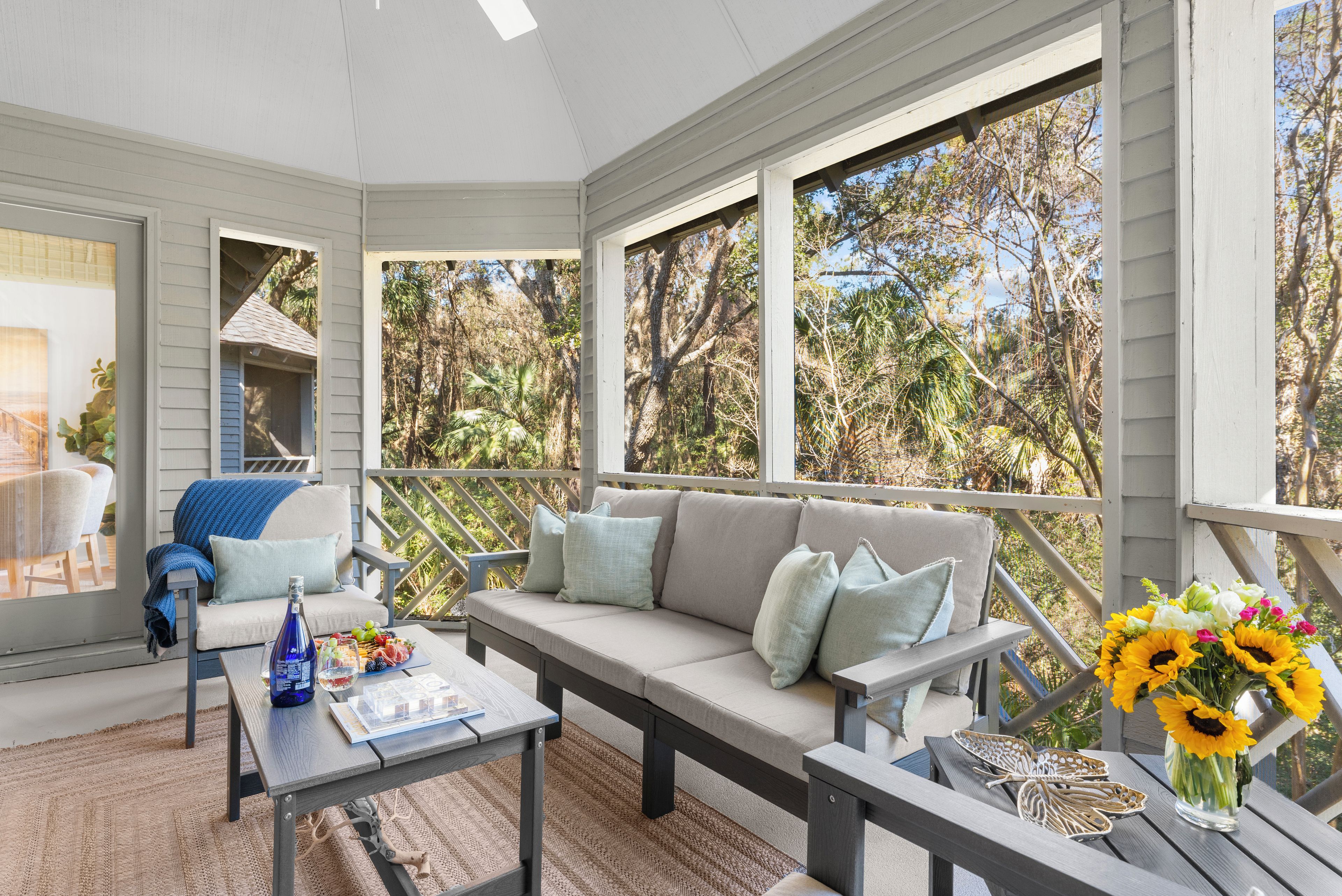 A covered outdoor seating area with a sofa, chairs, and a table.