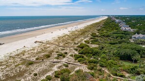 A coastal area with a sandy beach, a wooden boardwalk, and a row of houses with a green landscape. - Villa Palma, newly renovated, central, in popular location (Johns Island)