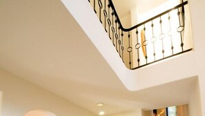 A spacious foyer with a wooden console table, a staircase with patterned steps, and a railing with a unique design. - Villa Torres Cozumel is a Private Luxurious Oceanfront  Home (Cozumel)