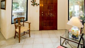 A spacious room with large windows, a wooden door, and a glass table with a lamp. - Villa Torres Cozumel is a Private Luxurious Oceanfront  Home (Cozumel)