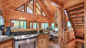 L’intérieur d’une cabane en rondins comprend une cuisine, un coin repas et un escalier.