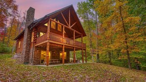 Une cabane en rondins dotée d’un balcon, entourée du feuillage automnal.