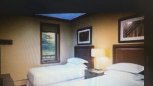 A bedroom with two beds, a window, a framed picture, and a bedside table with a lamp. - Spend the week at Valdoro Mountain Lodge & quaint Breckenridge Village - (Breckenridge)