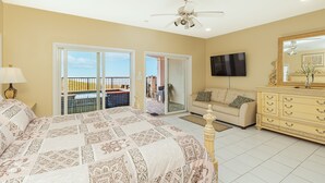 Ein Schlafzimmer mit einem großen Bett, einer Schlafcouch, einem Fernseher und einem Balkon mit Aussicht.