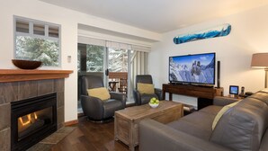 Ein modernes Wohnzimmer mit Kamin, Ledersofas, einem Couchtisch und einem Fernseher.