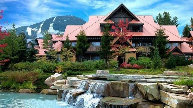Ein Hotel mit Wasserfall, umgeben von üppiger Vegetation und einem Bergpanorama.