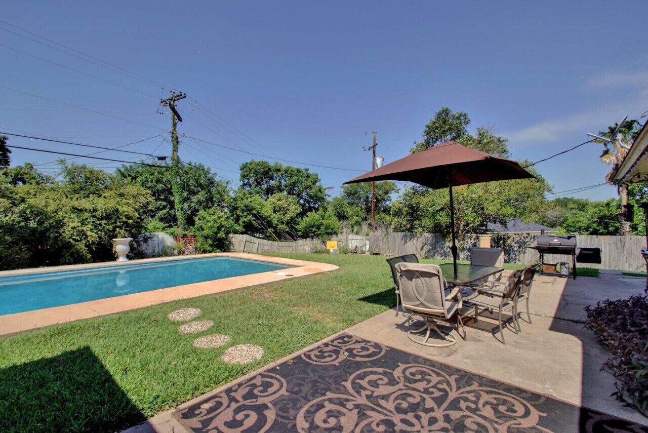 Un jardin avec une piscine, du mobilier de jardin et un barbecue.