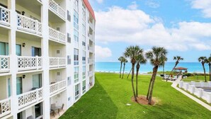 Un hôtel à plusieurs étages doté de balcons, d’une pelouse verdoyante, de palmiers et offrant une vue sur l’océan.